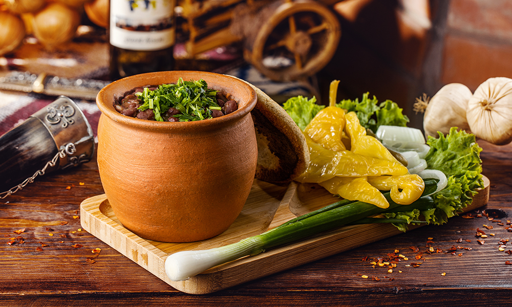 Beans(lobio) in a pot with assorted pickles - Georgian dish at Tbilisuri Ezo restaurant in Tbilisi }}